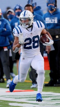 a football player running with the ball in his hand and other players behind him watching