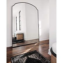 a large mirror sitting on top of a wooden floor next to a black and white rug