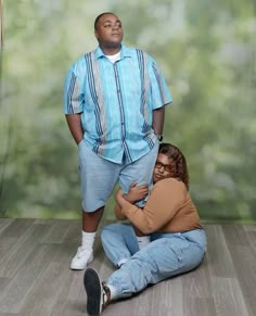 a man and woman sitting on the floor in front of a wall