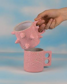 a hand is reaching for a pink cup that has been placed on top of each other