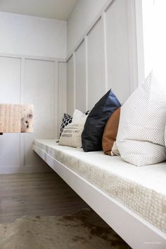 a row of pillows sitting on top of a white bench in front of a window