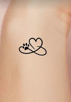 a dog paw and heart tattoo on the back of a woman's arm