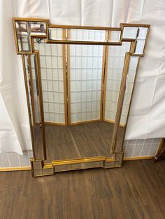 a large mirror sitting on top of a wooden floor next to a white sheet covered wall