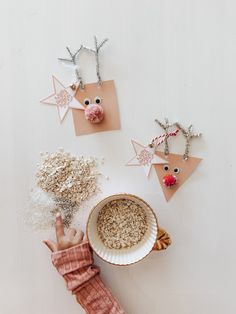 a child's hand reaching for some cereal in a bowl with reindeer decorations on it