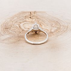 a diamond ring sitting on top of a piece of wood