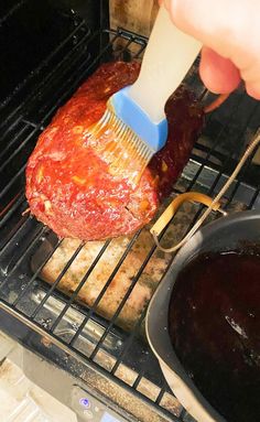 someone is using a brush to brush the meat in the oven