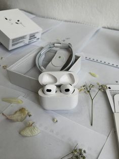 an apple airpods sitting on top of a table next to a laptop and flowers