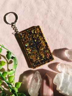 a cross keychain sitting on top of a table next to crystals and plants