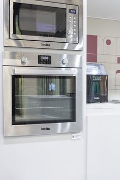 two ovens side by side in a kitchen with white counter tops and stainless steel appliances