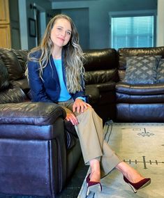 a woman sitting on top of a couch in front of a black leather recliner