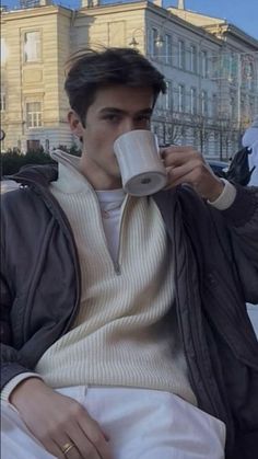 a man sitting on a bench drinking from a cup