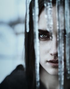 a woman with long hair is looking through the bars in front of her face and eyes