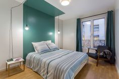 a bed room with a neatly made bed next to a window and a night stand