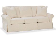 a white couch with four pillows on it's back and one arm facing the camera