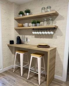 two wooden stools sit in front of a counter with shelves on the wall behind them