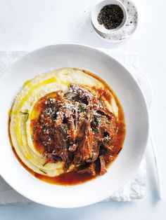 a white bowl filled with food on top of a table next to a fork and spoon