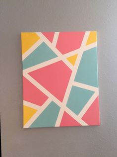 an abstract painting on the wall with different colors and shapes, including triangles in pink, blue, yellow, green, and orange