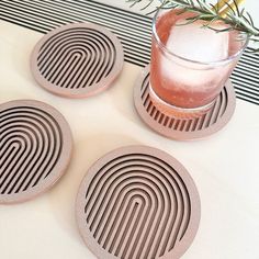 three coasters sitting on top of a table next to a glass with a drink in it