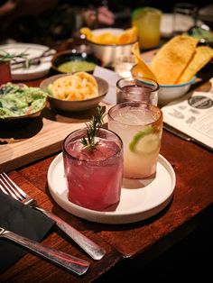 there are two drinks on the table with other food and utensils around it