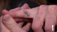 a person with a small cross tattoo on their left hand