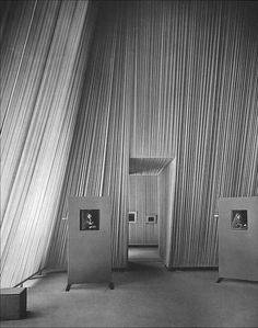 an old black and white photo of two doors in front of a curtained wall