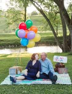 a man and woman sitting on a blanket with balloons