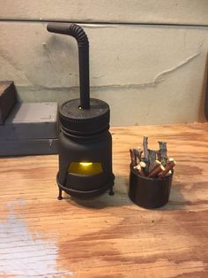 a small black stove sitting on top of a wooden table next to a cup filled with matches