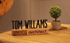 a small potted plant sitting on top of a wooden block that says tom williams