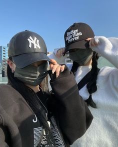 two people wearing new york yankees hats and covering their faces with black face coverings