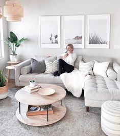 a woman sitting on top of a couch in a living room next to a coffee table