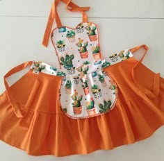 an orange and white dress with cactus print on the front, attached to a headband