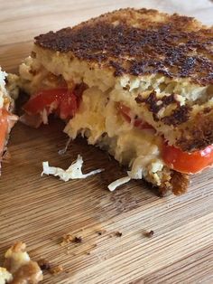 a grilled cheese and tomato sandwich cut in half on a cutting board with one bite taken out