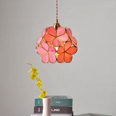 a lamp that is on top of a table next to some books and a vase