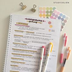 three pens and two notebooks sitting next to each other on top of a table