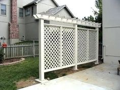 a white trellis on the side of a house next to a yard and fence