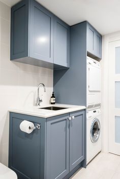 a washer and dryer in a small room with blue cabinets on the walls