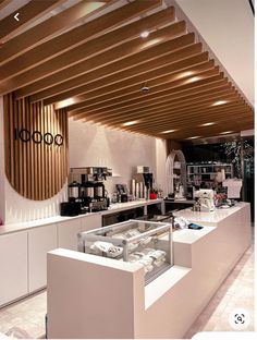 the interior of a coffee shop with white counter tops and wood slats on the ceiling