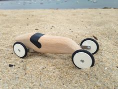 a wooden toy car sitting in the sand