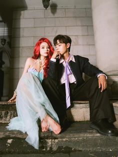 a man and woman sitting on steps next to each other wearing formal clothes with long red hair