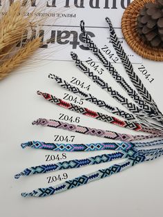 six different colored braided hair ties sitting on top of a table next to a pine cone