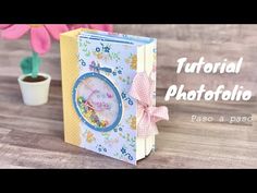 a small book with a clock on the cover and a flower pot in the background