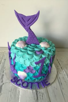 a cake decorated with blue and purple icing, topped with an image of a mermaid tail