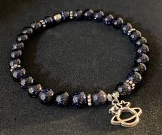 Genuine blue goldstone and pyrite accent beads with silver tone tiny Saturn charm. Beads are 6mm. Bracelet is 6.5 inches inner length around and made with crystal stretch elastic cord. Saturn Charm, Goldstone Bracelet, Flag Beads, Blue Goldstone, Charm Beads, Gemstone Bracelet, Bead Charms, Gemstone Beads, Silver Tone