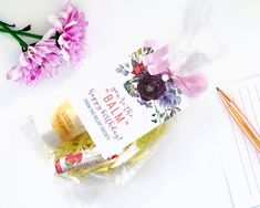 a package of soap next to some flowers and pencils on a white table with writing paper