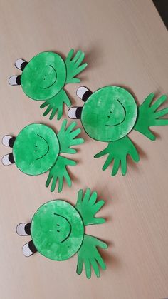 three green paper cut outs sitting on top of a wooden table