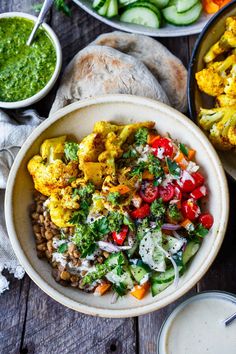 a bowl filled with rice and vegetables next to other bowls full of food on a wooden table