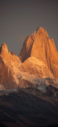 the mountains are covered in snow as the sun is low to the ground on top