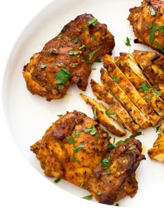 some chicken is on a white plate with green garnish and parsley in the middle