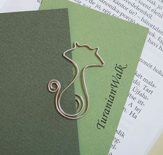 a metal cat brooch sitting on top of an open book next to some papers