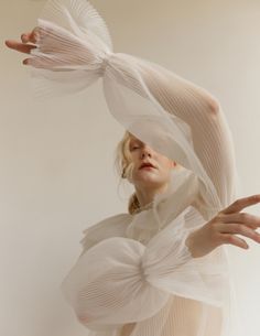 a woman with her hands in the air, wearing white clothing and veils over her head